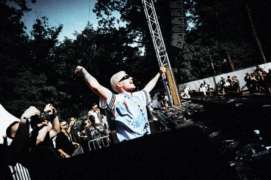 George live on a festival stage, arms up, crowd in the foreground
